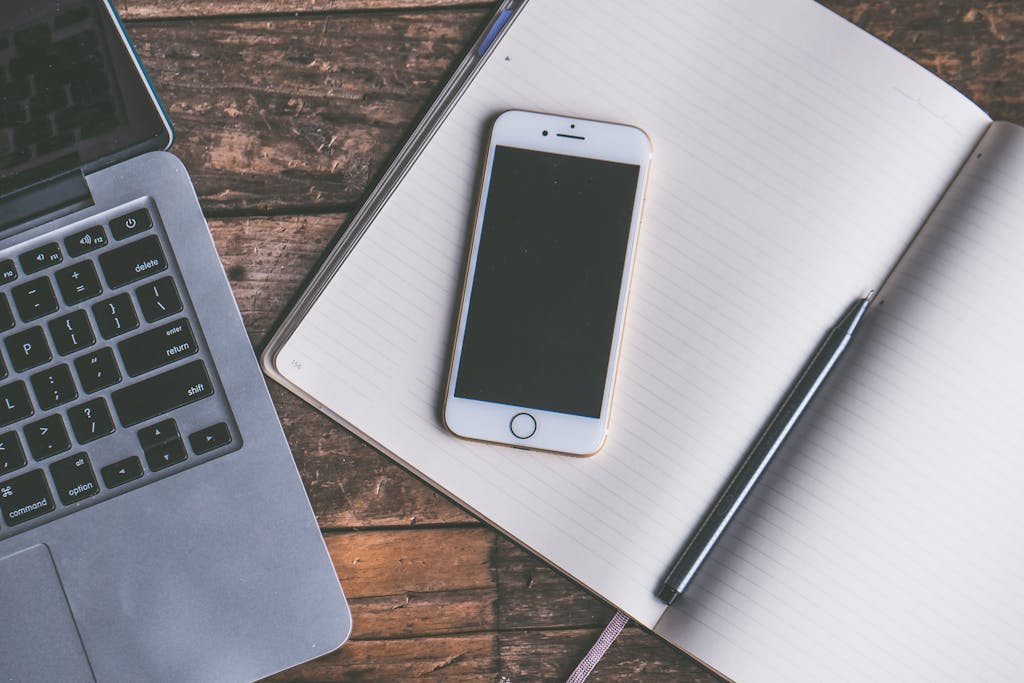 Flat Lay Photography of Gold Iphone on Opened Notebook Beside Pen